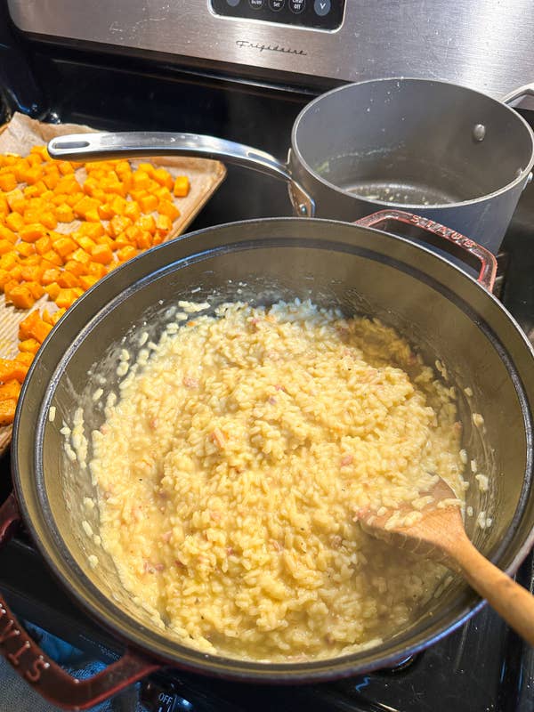 Creamy risotto in a Dutch oven on the stove, next to the roasted squash