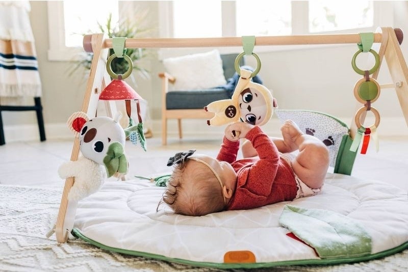 A baby plays with a baby gym