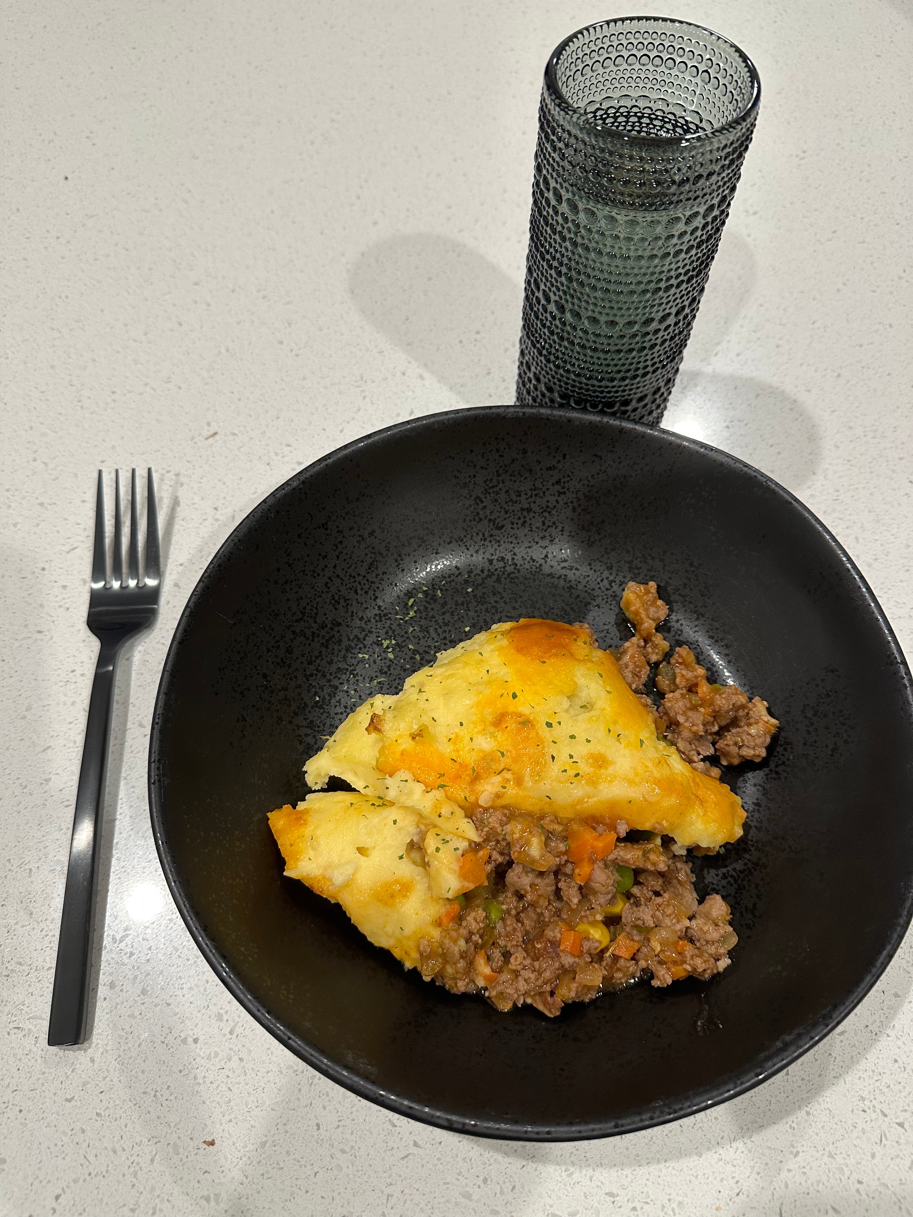 cottage pie in a bowl with a fork and glass