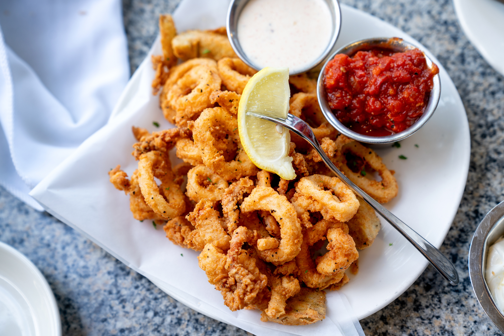 fried calamari on a plate with a lemon wedge and sauces