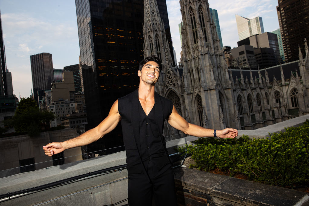 taylor on a rooftop with a city behind him