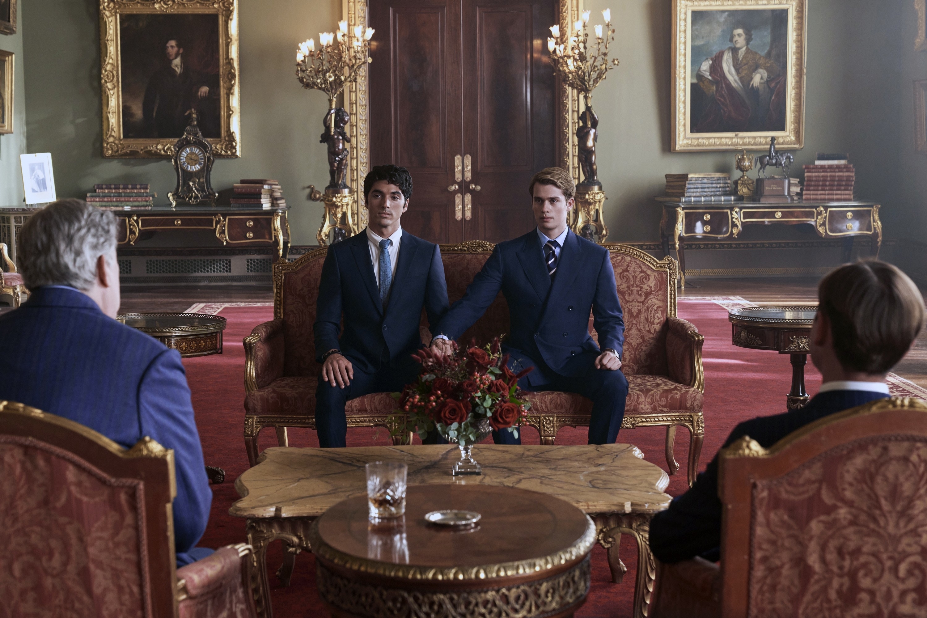 taylor and nicholas holding hands sitting in a regal room in the film