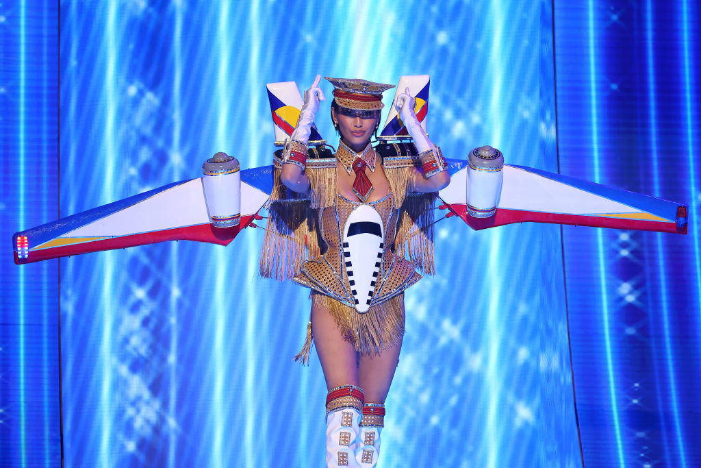 She&#x27;s wearing a fringed aviation-themed bodysuit with large wings and in the colors of the flag: red, white, blue, and yellow