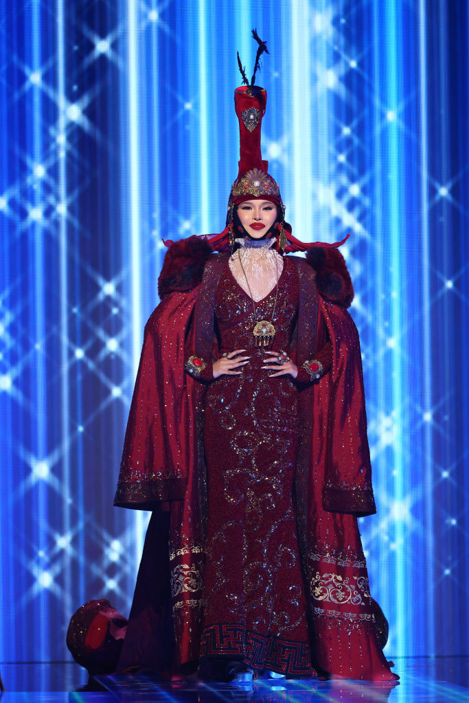 A long, bejeweled gown with long robe and headpiece
