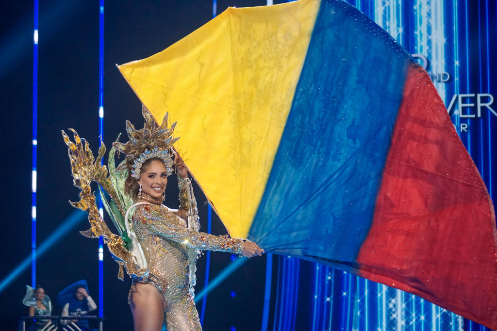 She&#x27;s carrying the colors of the flag — blue, red, and gold — and wearing an ornate, long-sleeved tasseled, bejeweled bodysuit with ornate headdress