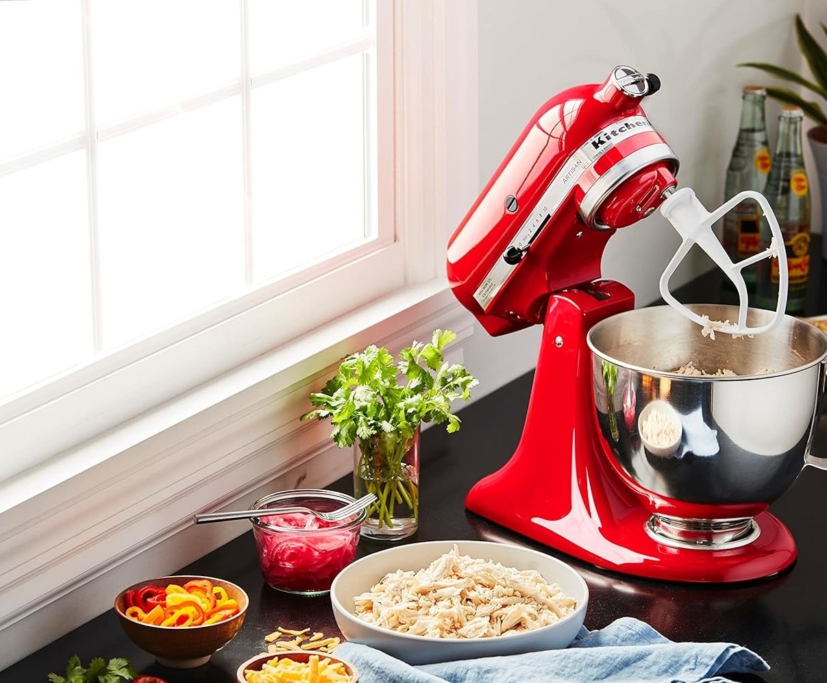 The red kitchenaid in use on a countertop