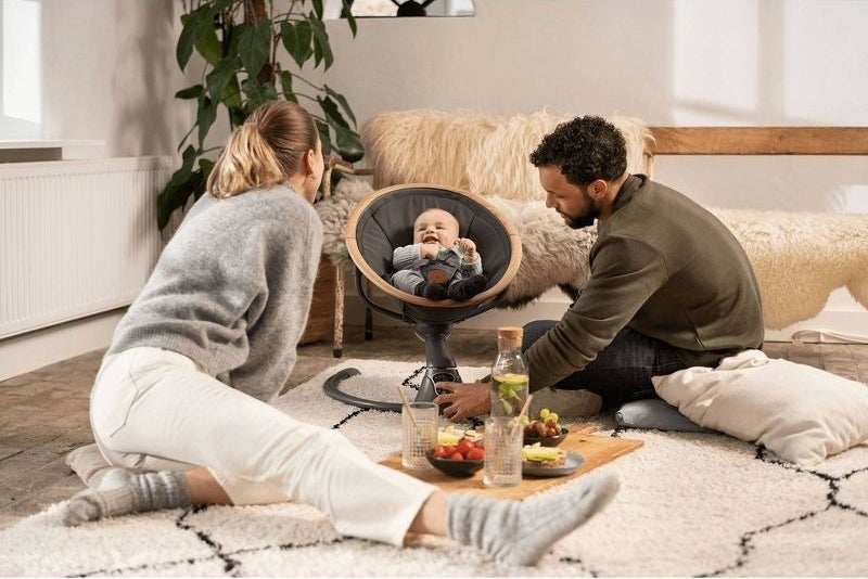Parents interact with a baby in a swing