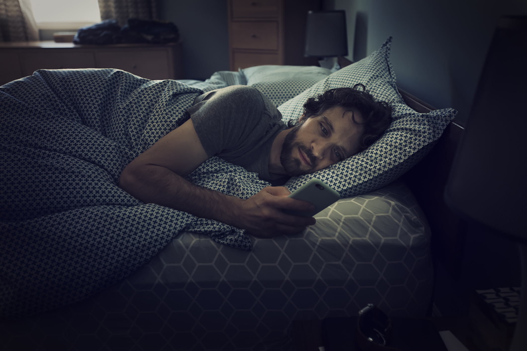 A man laying in bed and looking at his phone