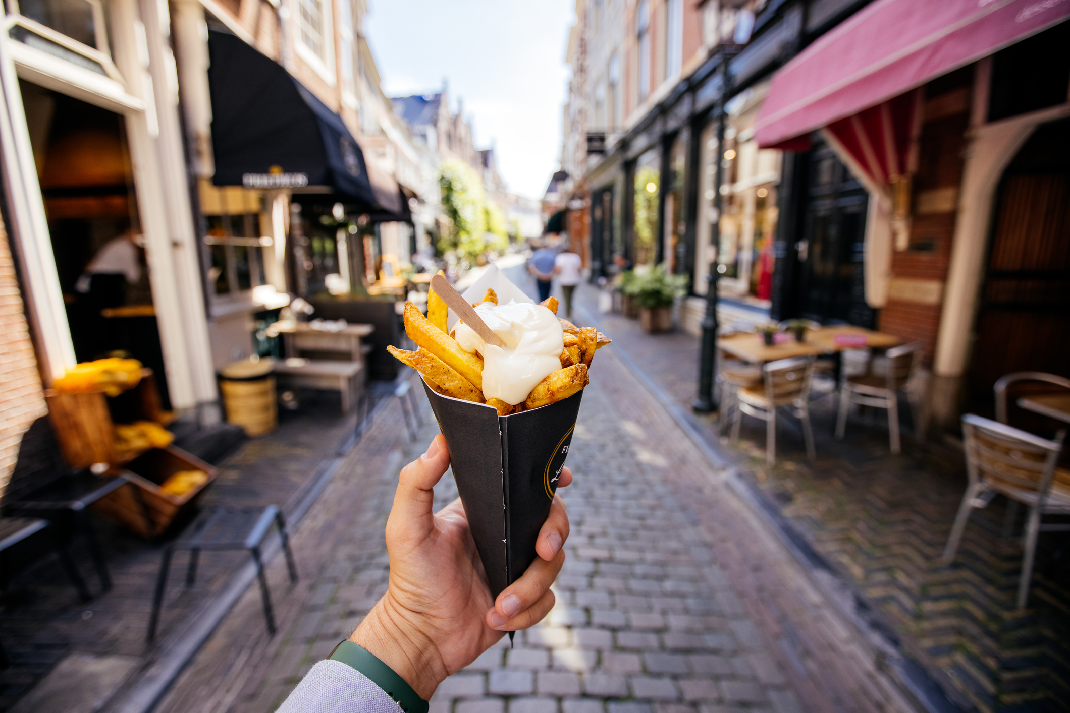 someone holding a cone of fries on a belgian street