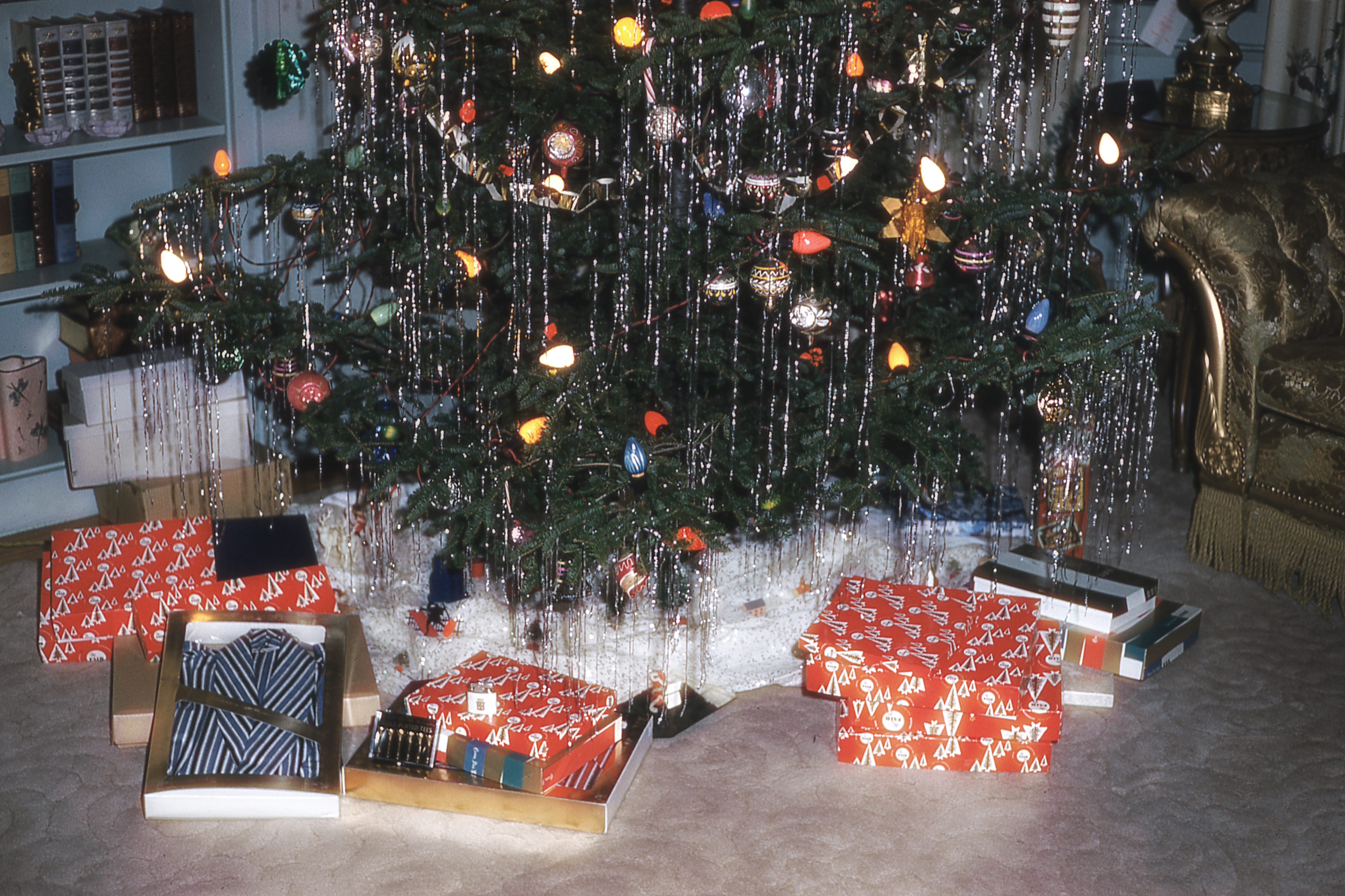 The base of a vintage Christmas tree, decorated with tinsel; presents are underneath