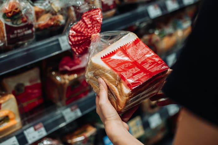 woman looking at a bagged loaf of bread in a grocery store