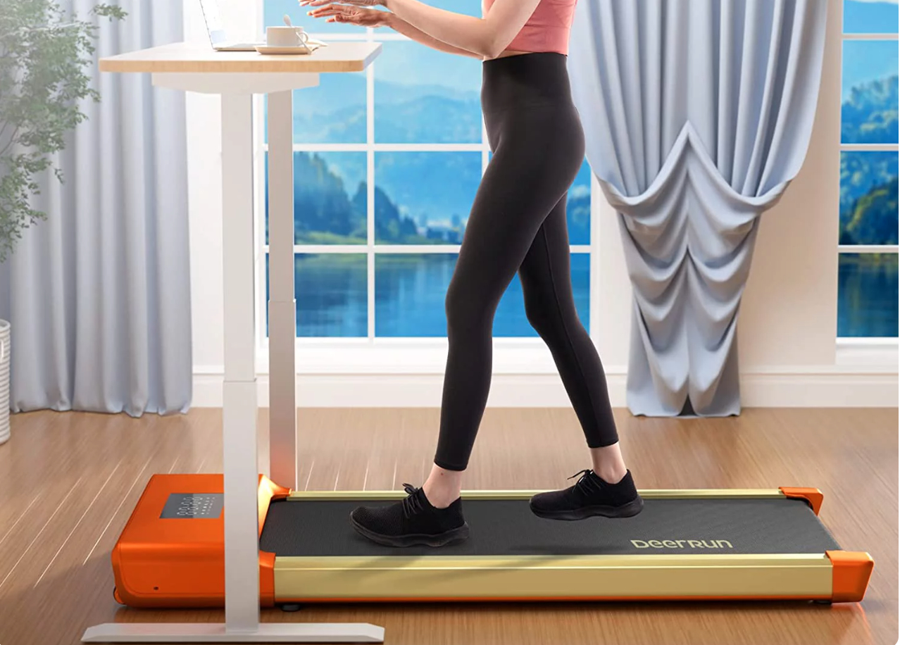 a woman standing on a walking pad as she works on a standing desk