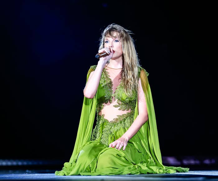 Close-up of Taylor performing onstage sitting on her knees