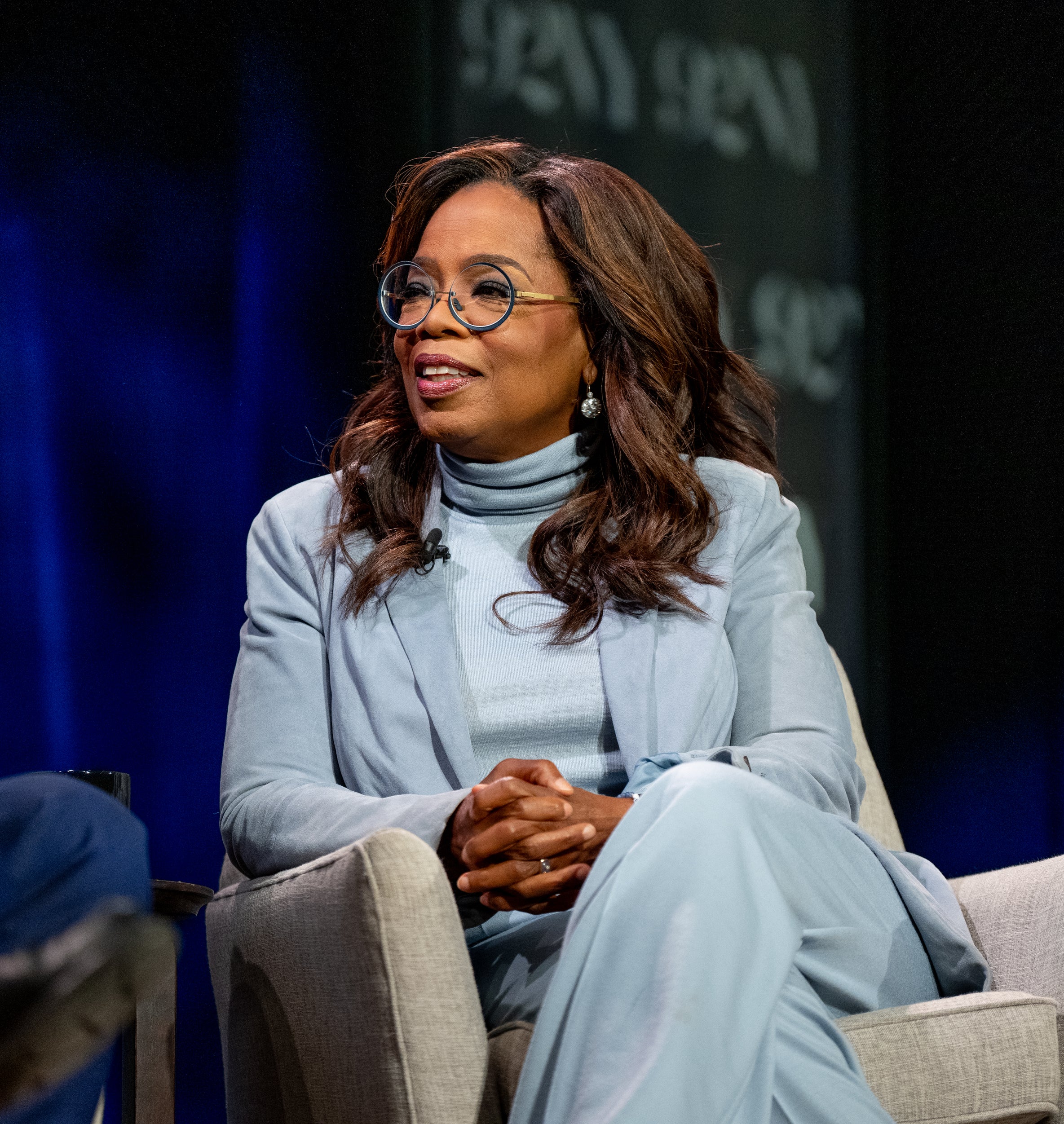 A close-up of Oprah sitting onstage