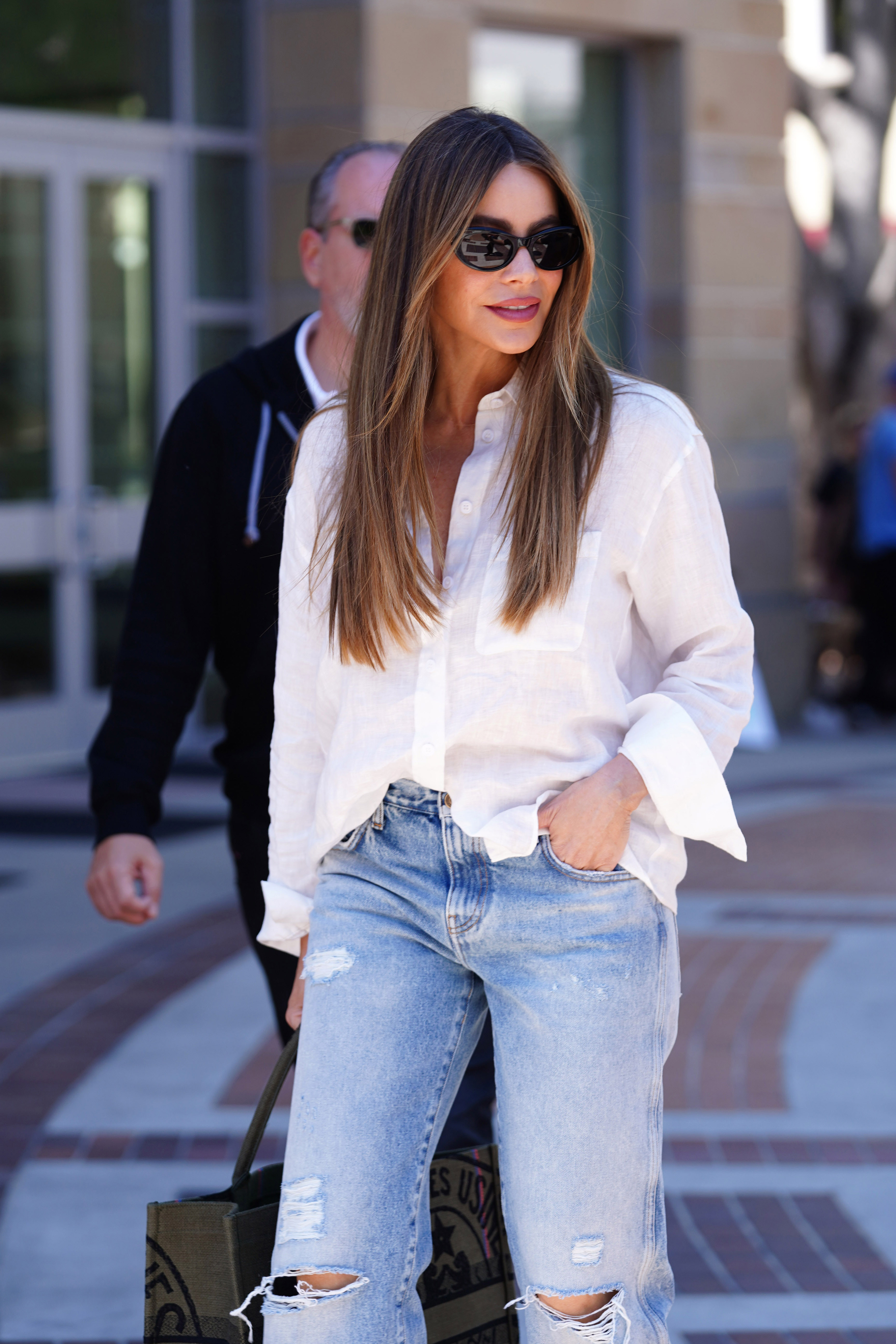 Sofia Vergara walking outside in a blouse and ripped jeans