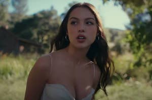 Olivia Rodrigo standing in a field in the Can't Catch Me Now music video