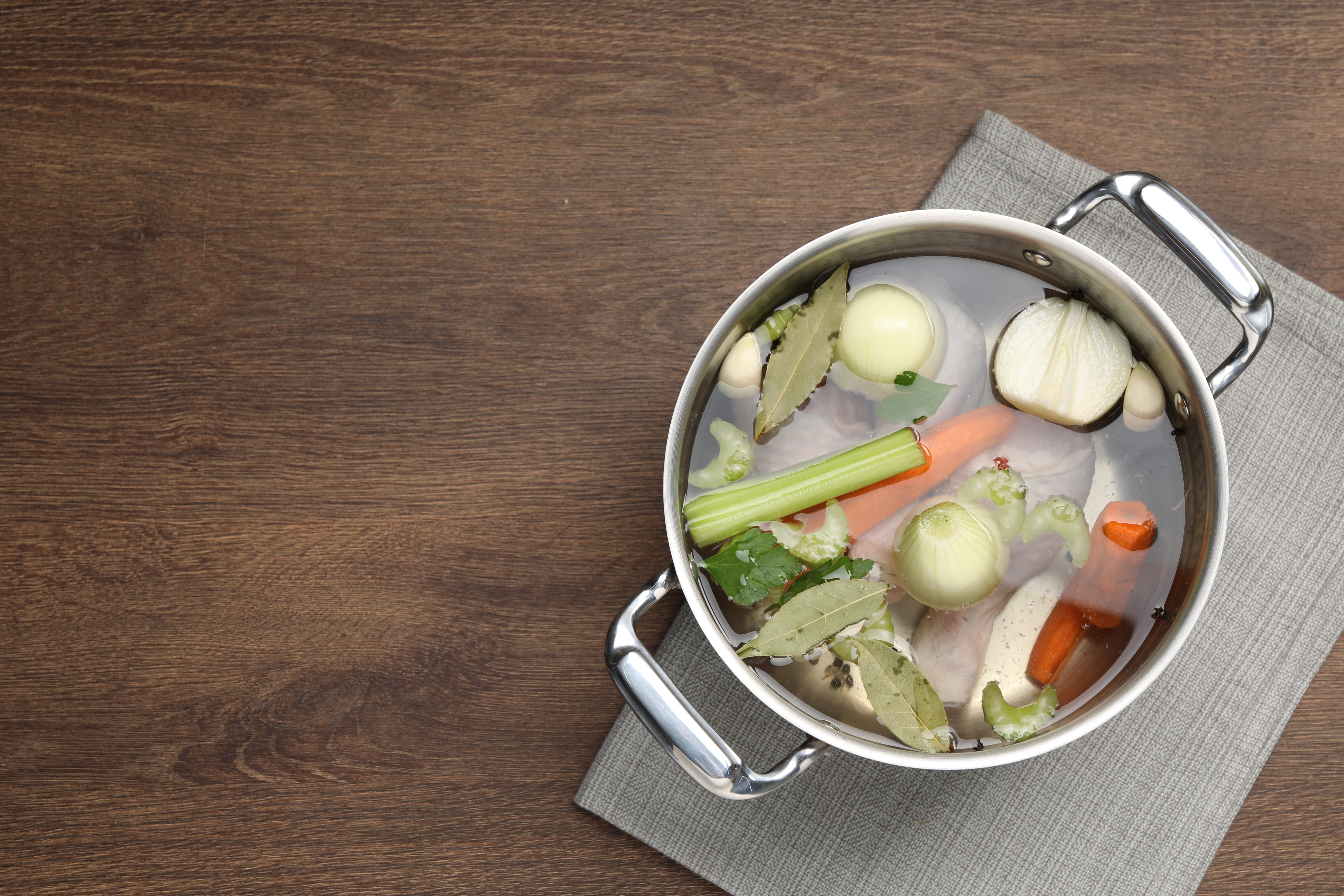 a shot of a pan fulled with uncooked carrots, celery, onion, and meat to create a broth