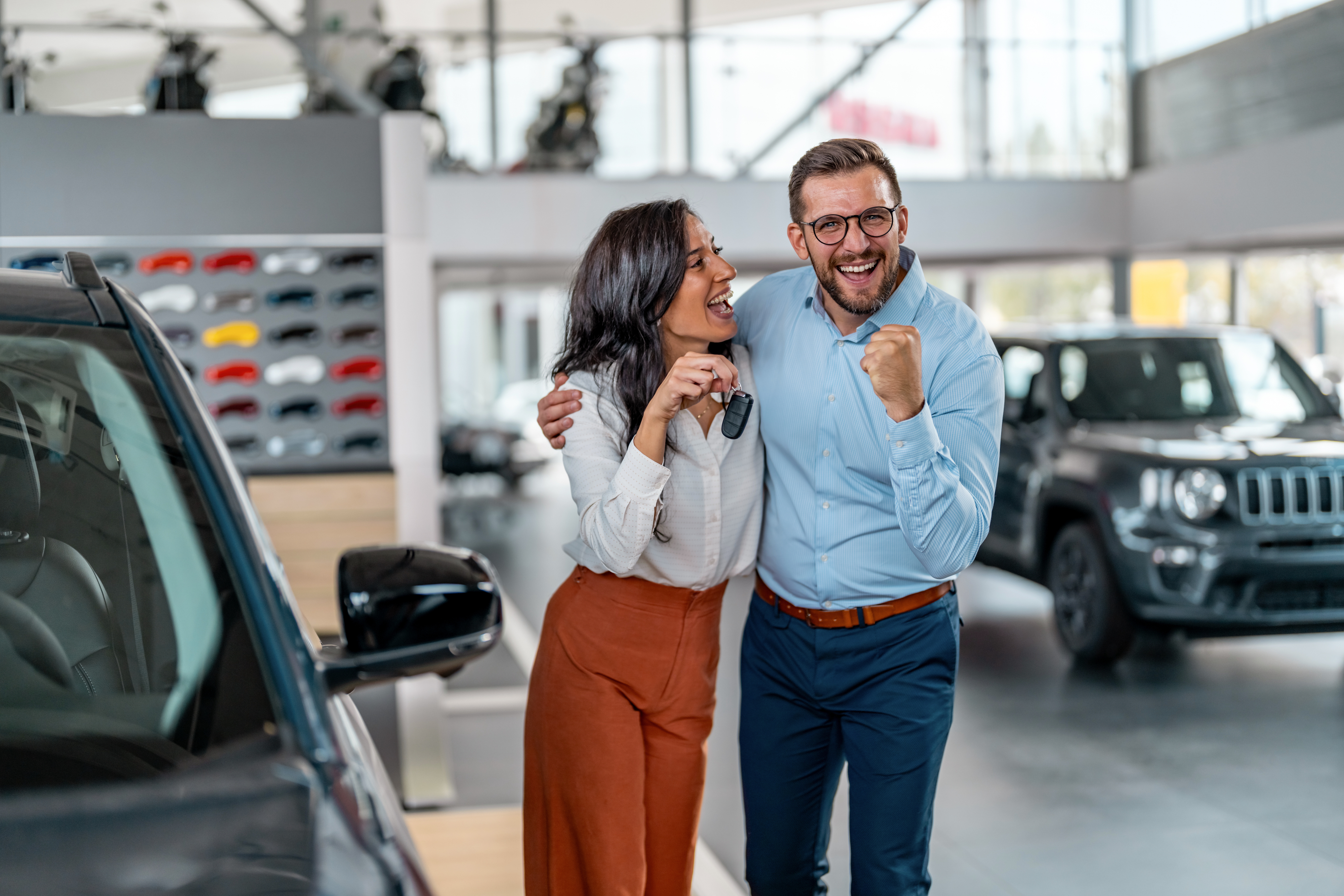 A couple holding keys to a new car