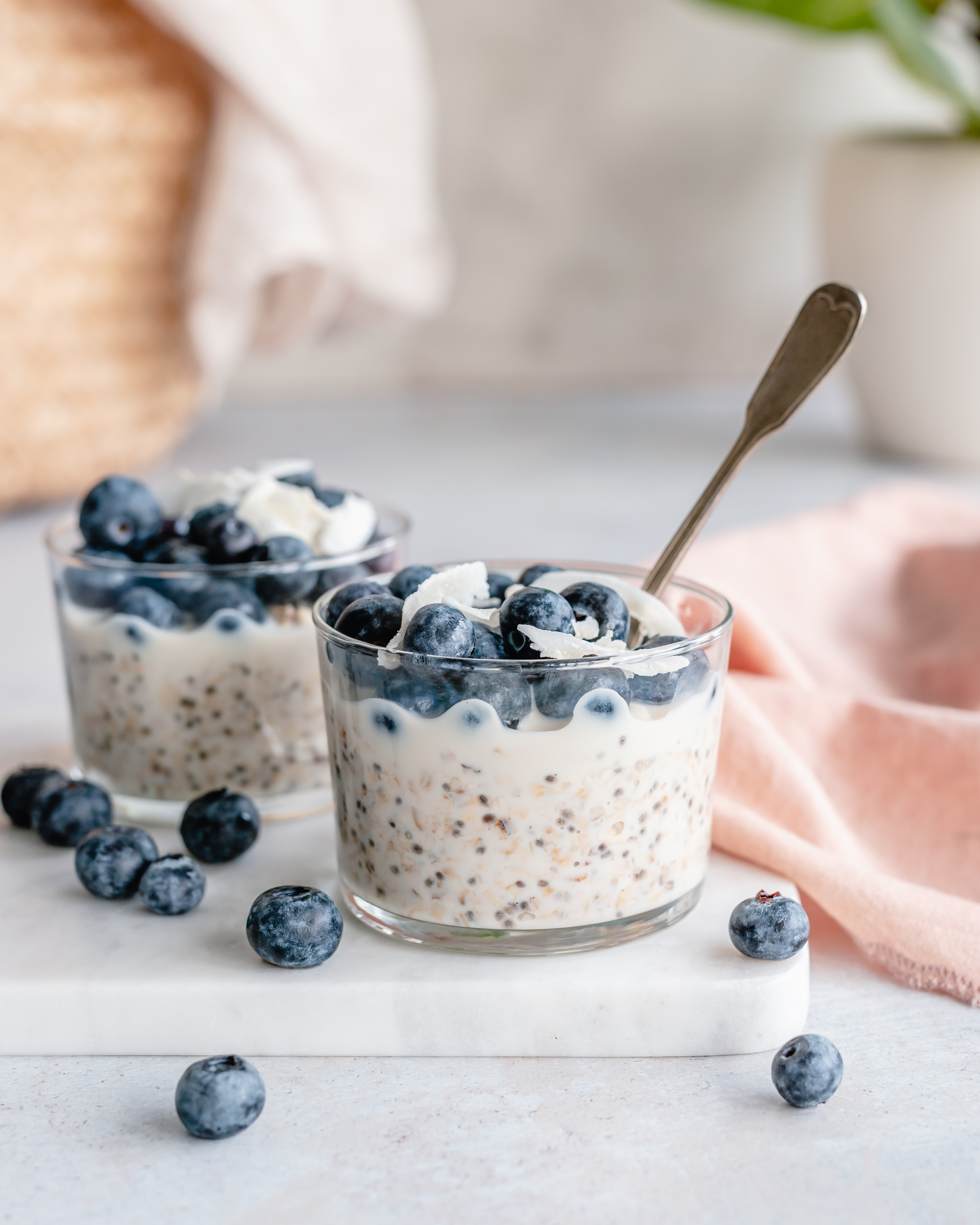two cups of overnight oats topped with fresh blueberries