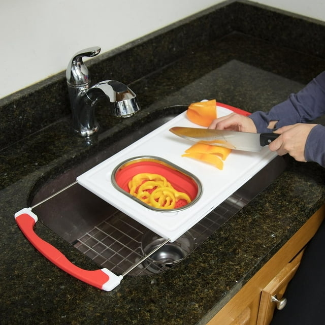 white and red cutting board with peppers over a kitchen sink