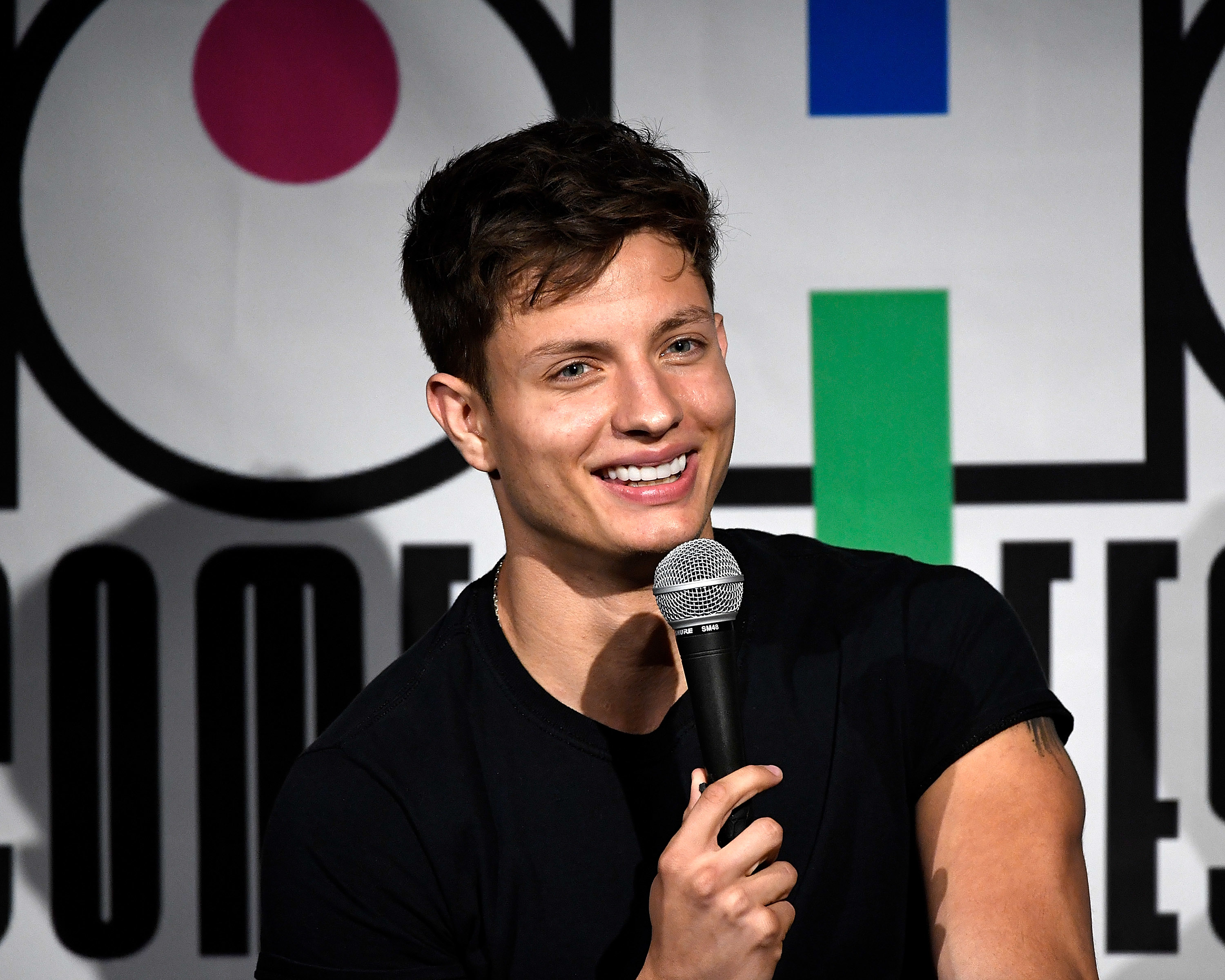 Closeup of Matt Rife smiling as he holds up a mic