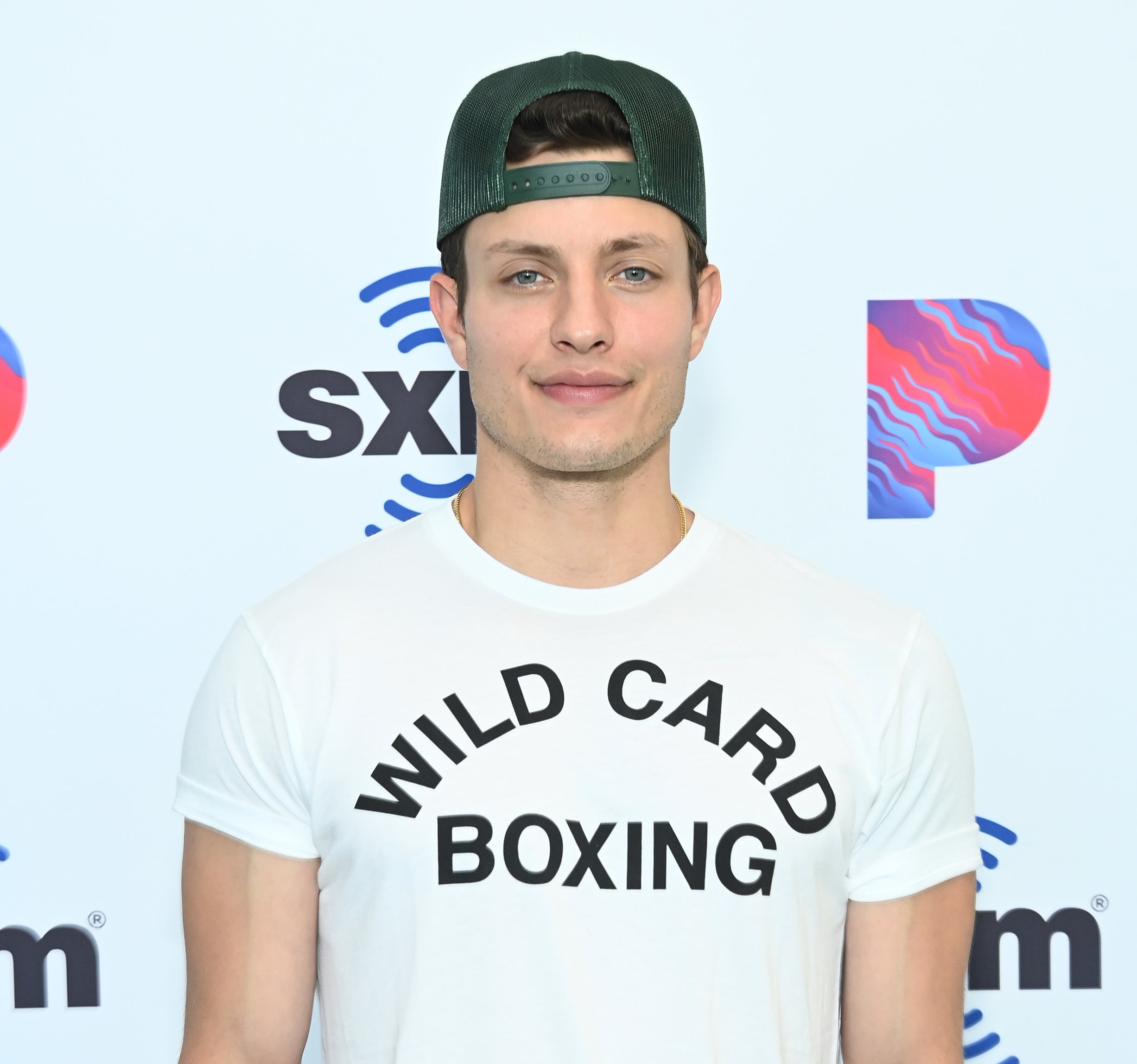 Closeup of Matt Rife on the red carpet wearing a baseball cap backwards and a t-shirt that says Wild Card Boxing