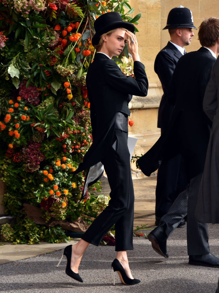 cara in a suit and top hat with heels