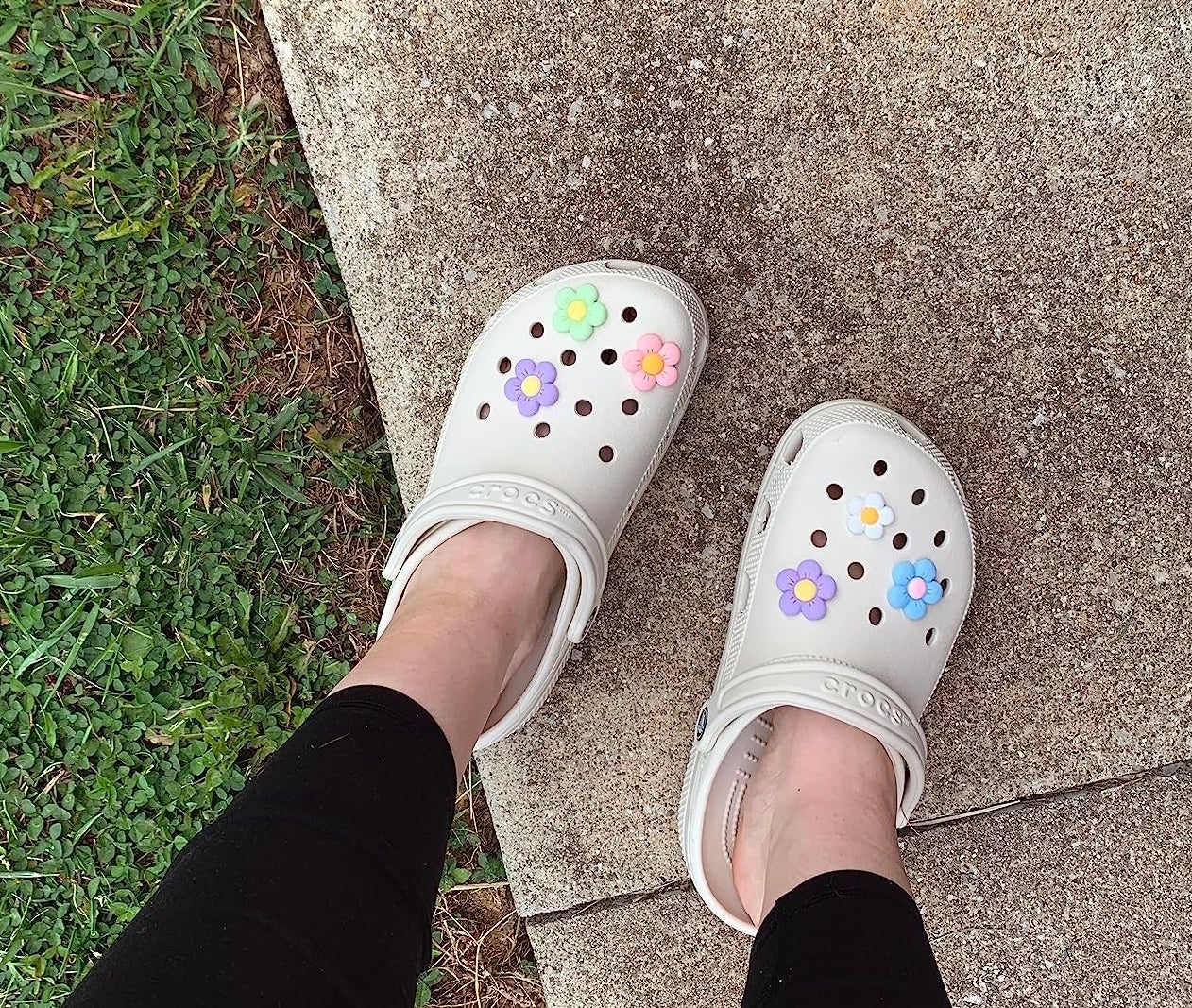 reviewer wearing white crocs with colorful flower charms on them