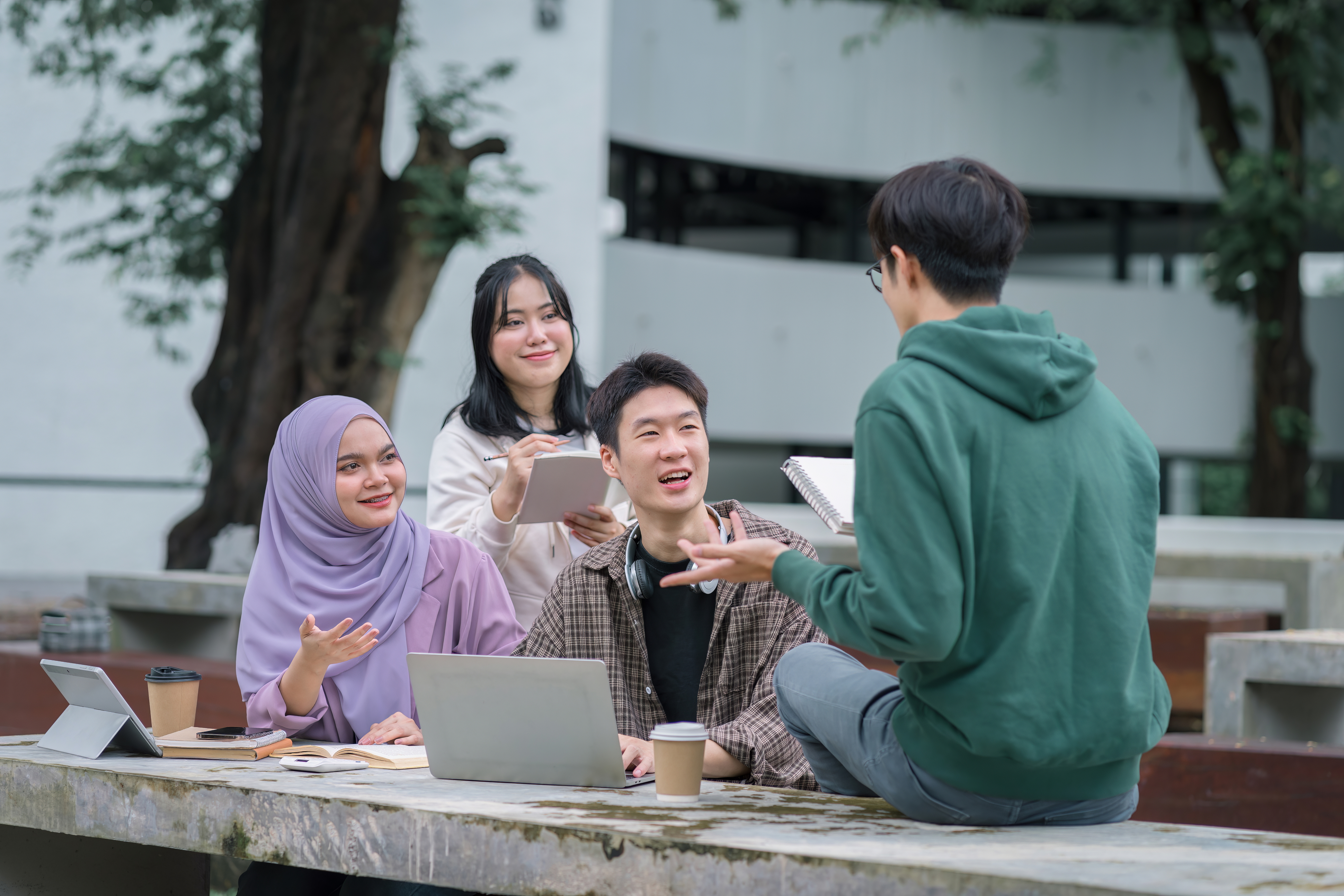 a group of four students sitting outside