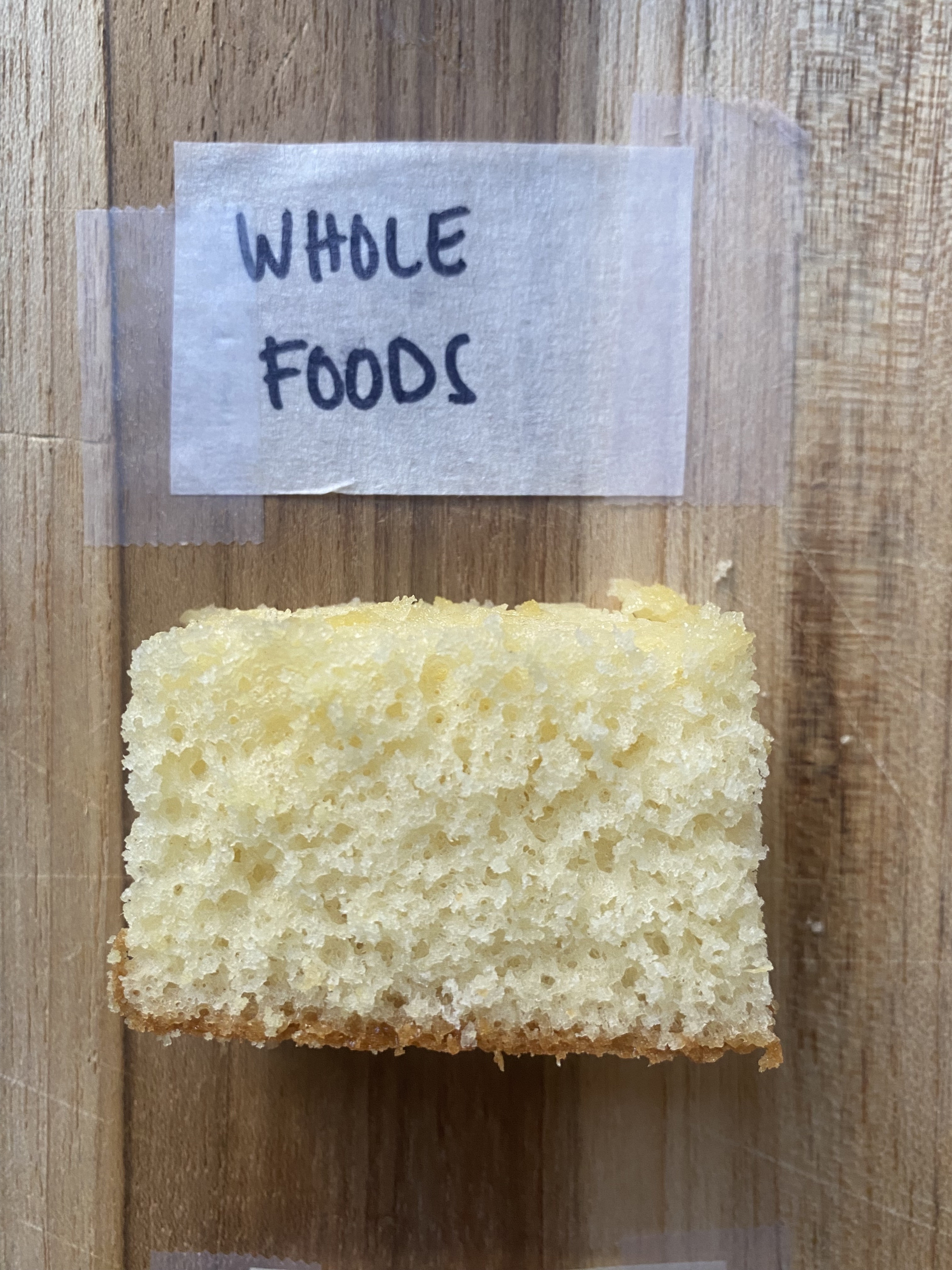 a piece of whole foods cake on a cutting board with tape labeling it