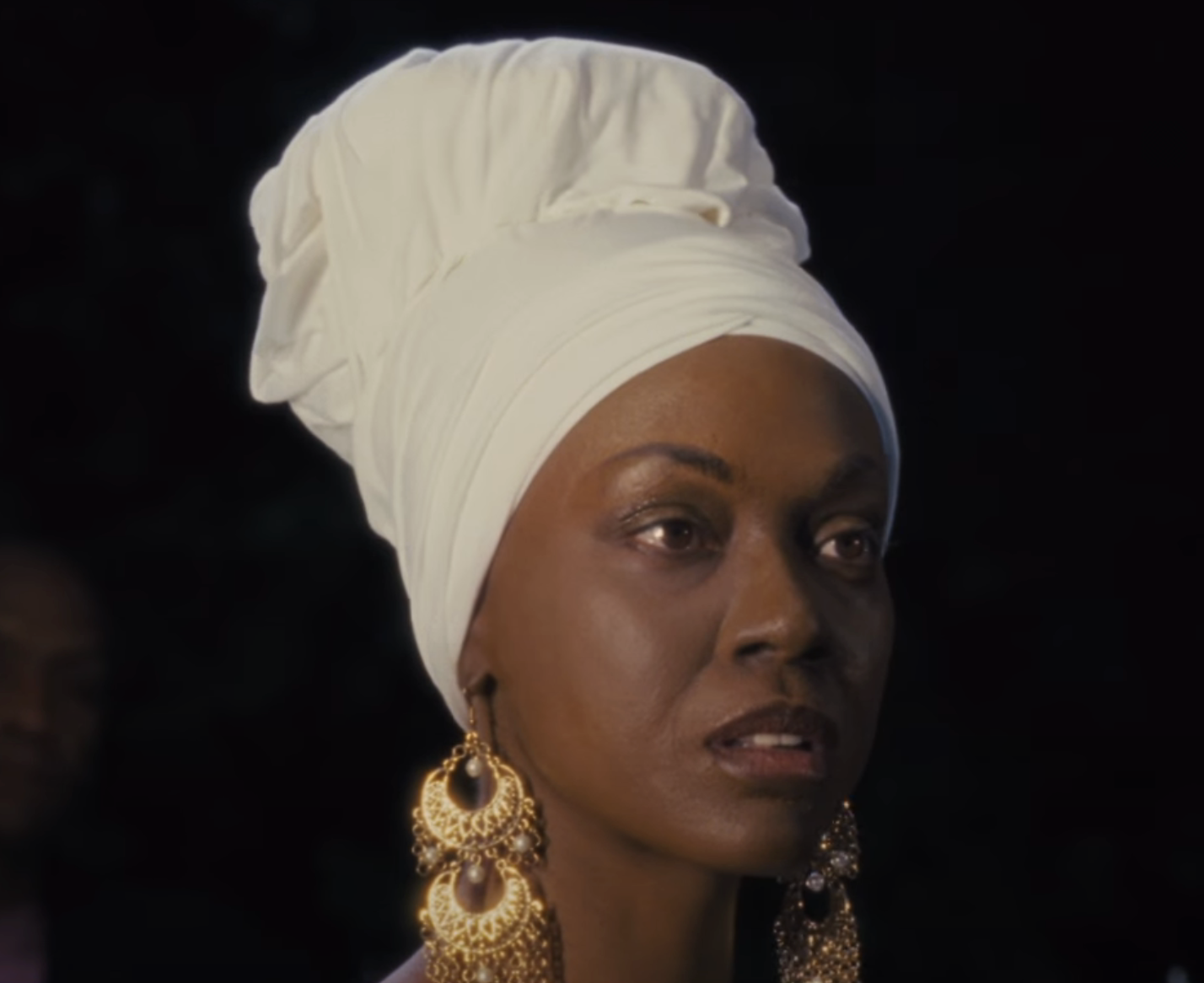 closeup of her wearing a headwrap and large earrings