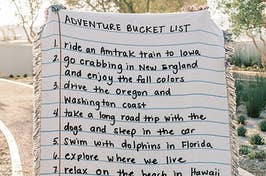 a giant blanket that looks like a piece of lined notebook paper and has an adventure bucket list on it