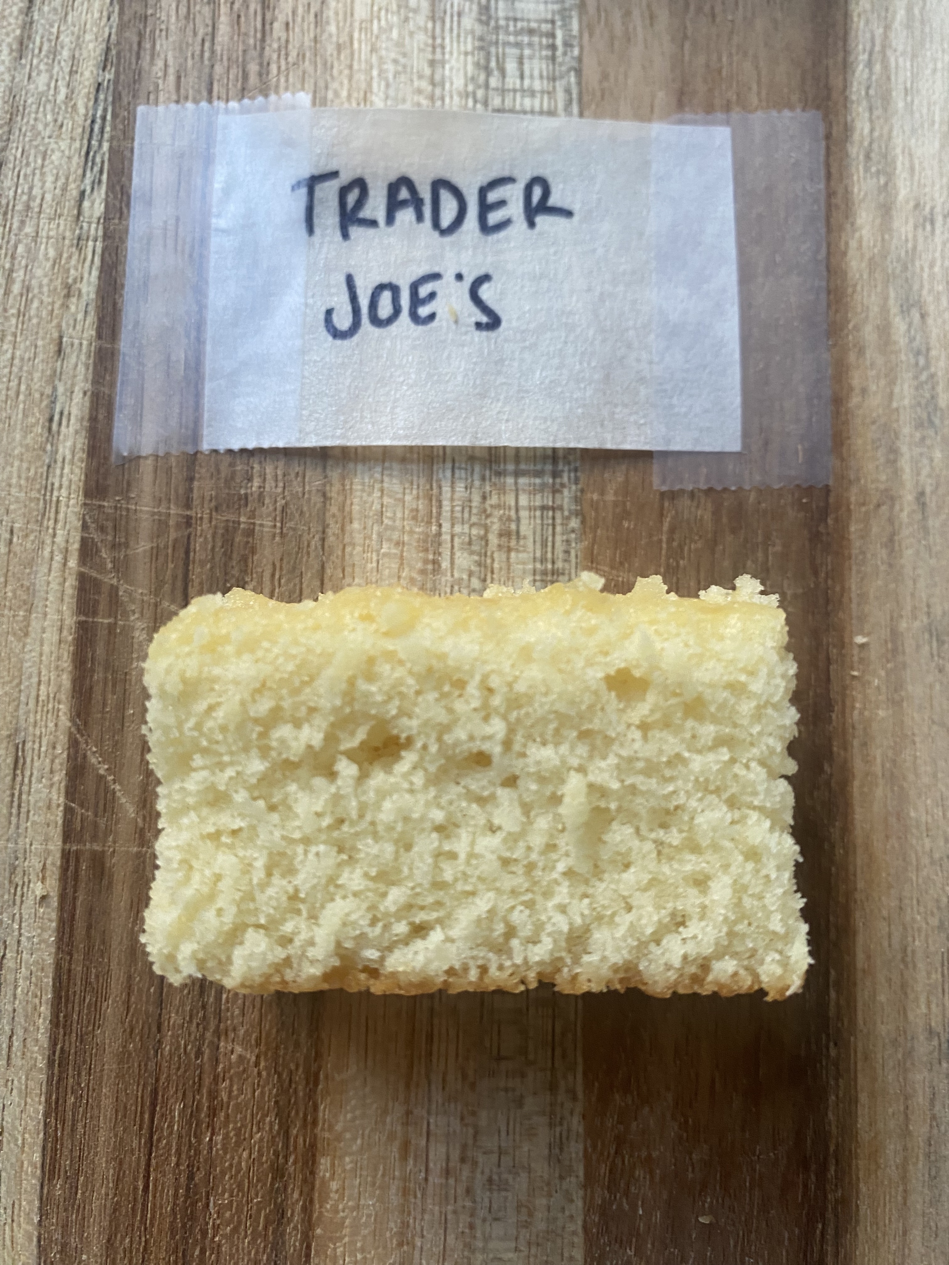 a slice of trader joe&#x27;s cake on a wooden cutting board with a label above it