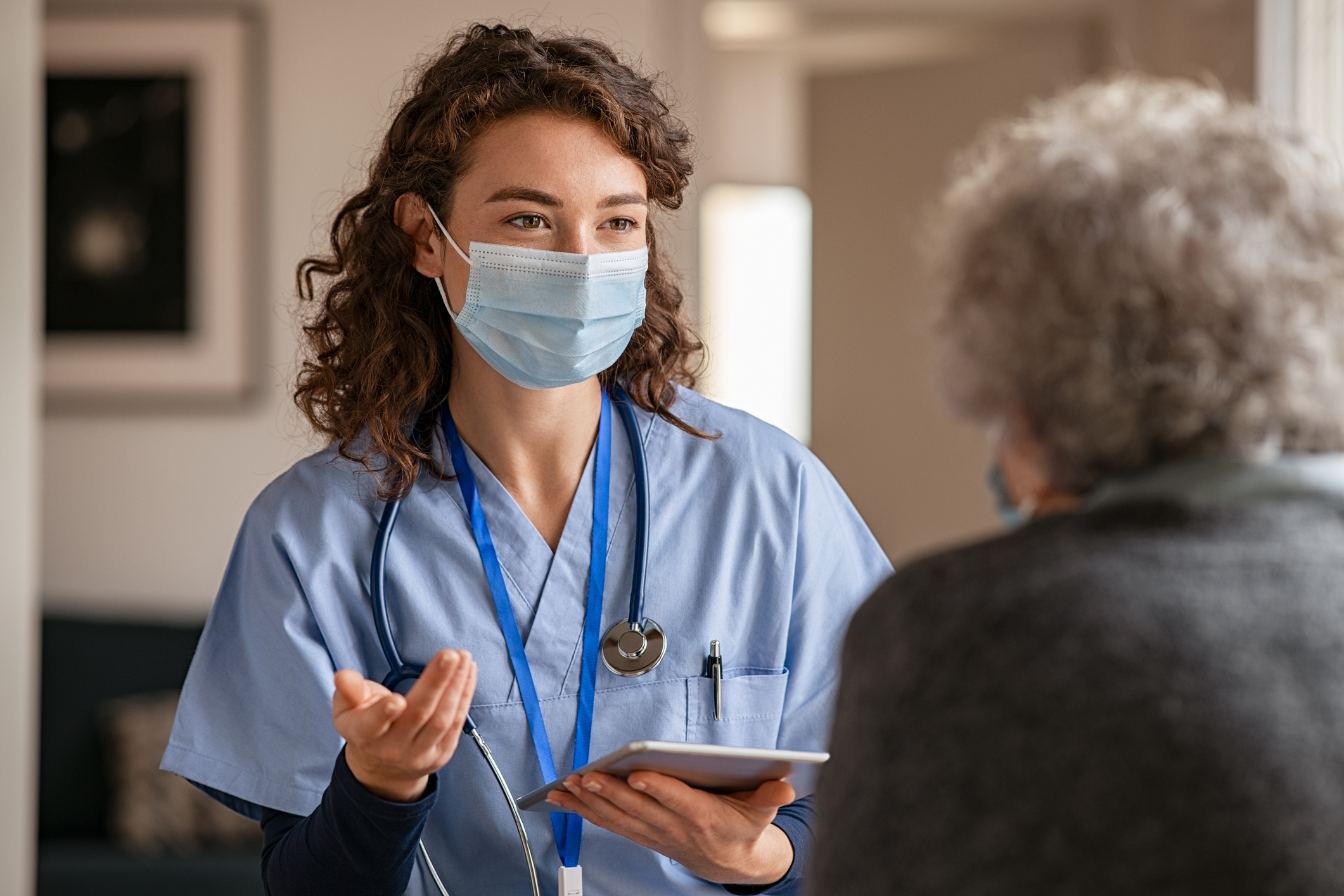 A nurse with a mask on talking to a patient