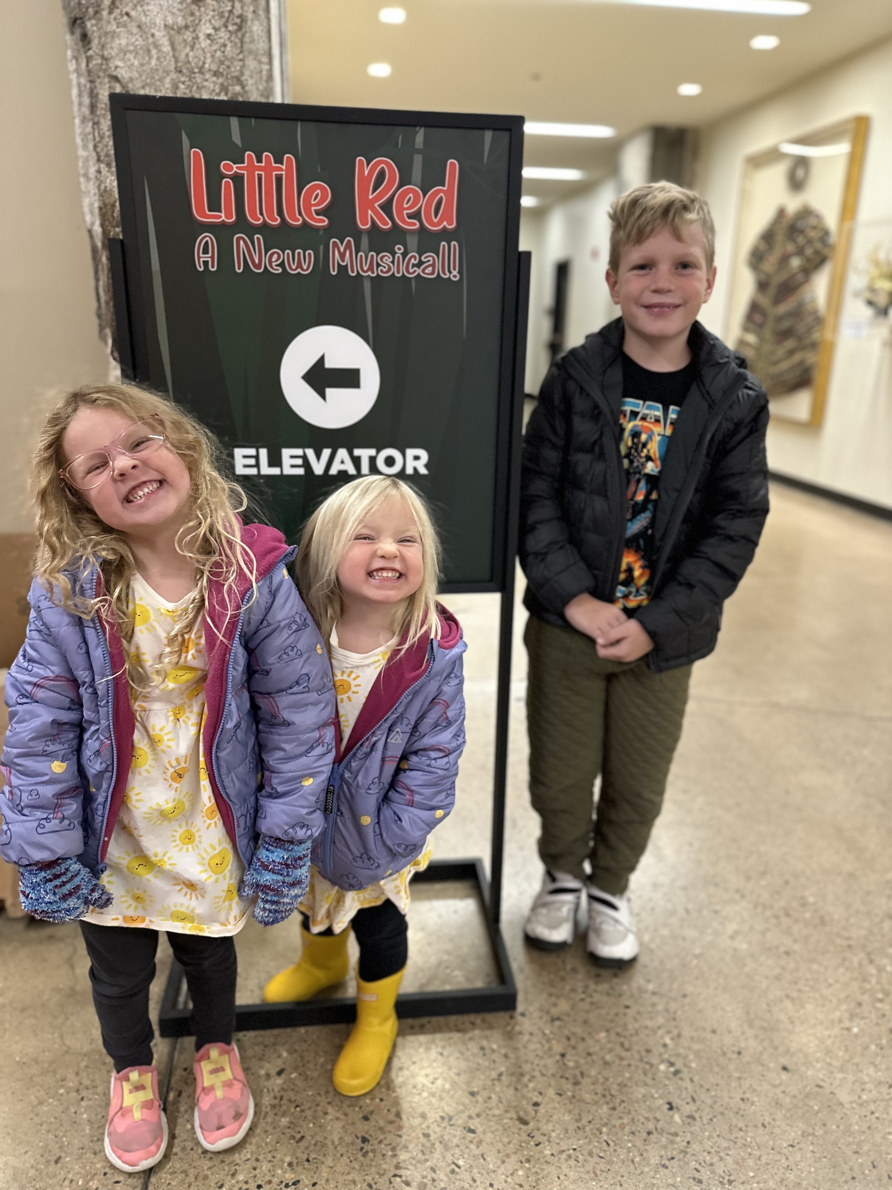 the author&#x27;s children next to a sign for Little Red: A New Musical