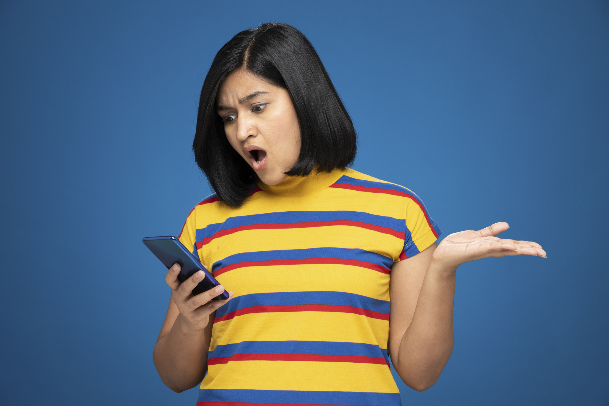 A woman looking flabbergasted at something on her phone