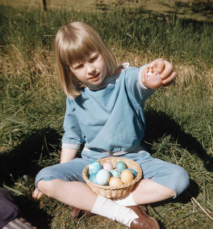 A photo of a young child holding a basket of Easter eggs in their lap