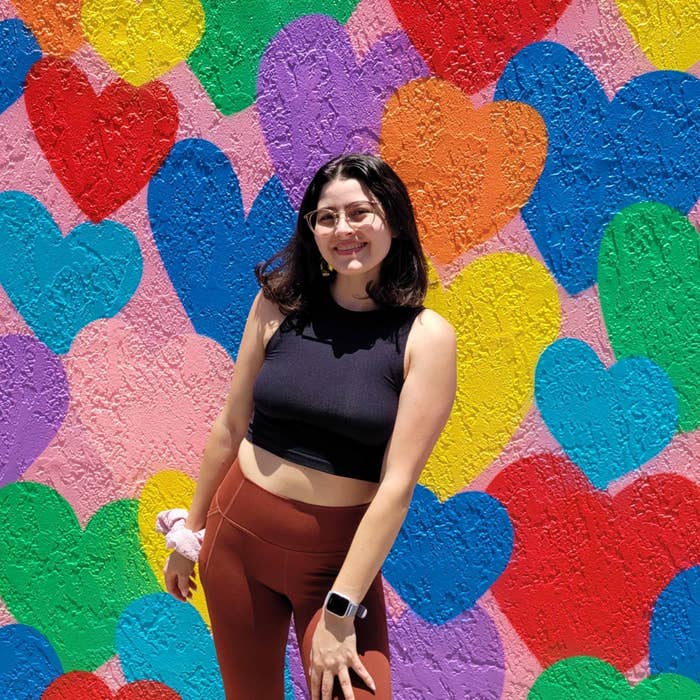 Nai&#x27;a standing in front of a wall painted with rainbow colored hearts