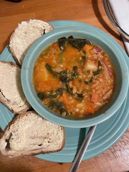 Bowl of lentil soup with buttered bread on the side