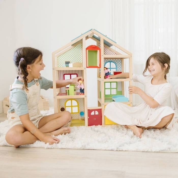 Two kids play with a dollhouse