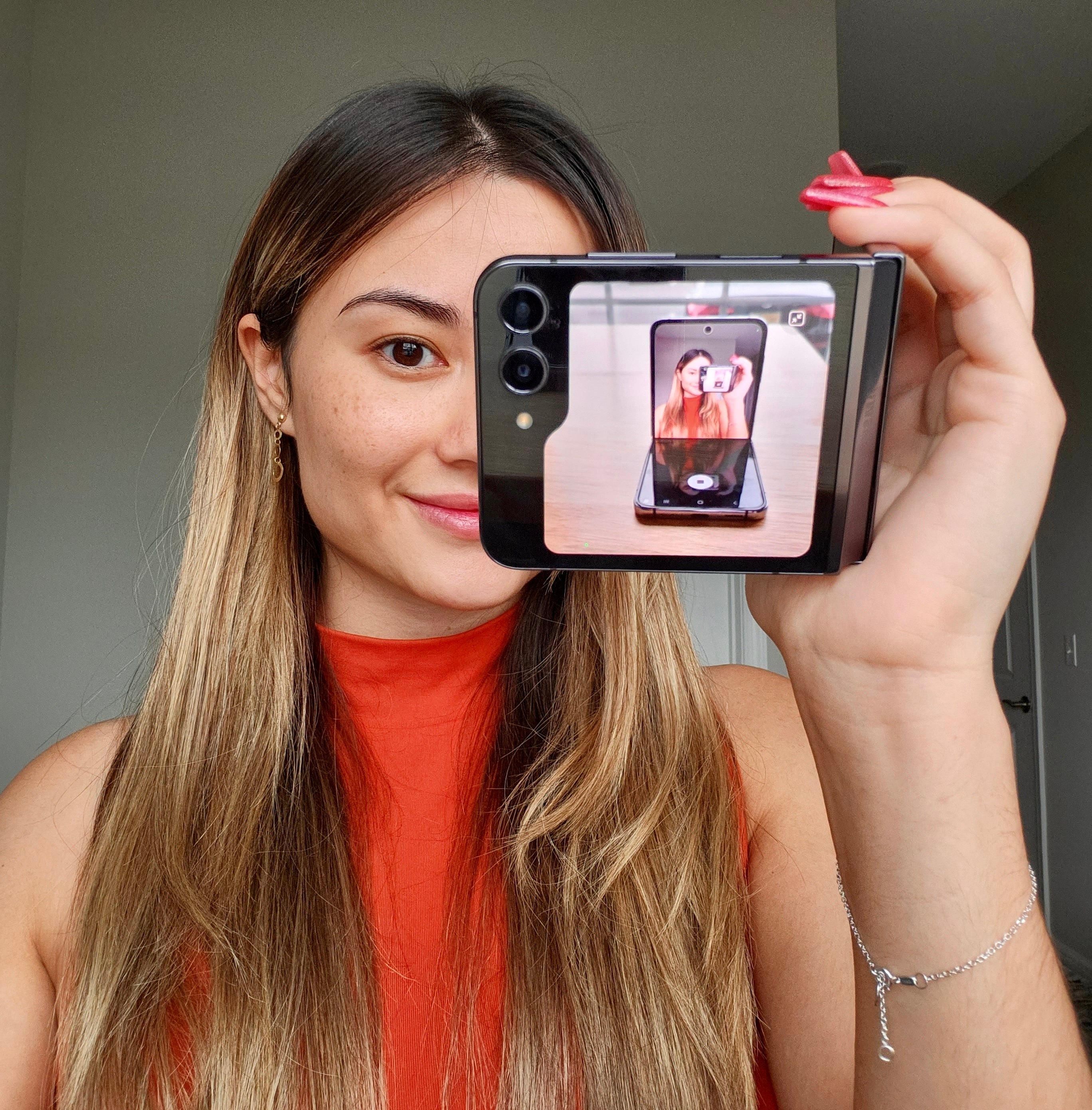 author holding Flip 5 folded sideways similar to a camcorder, with the cover screen viewfinder showing a picture of the Flip 4