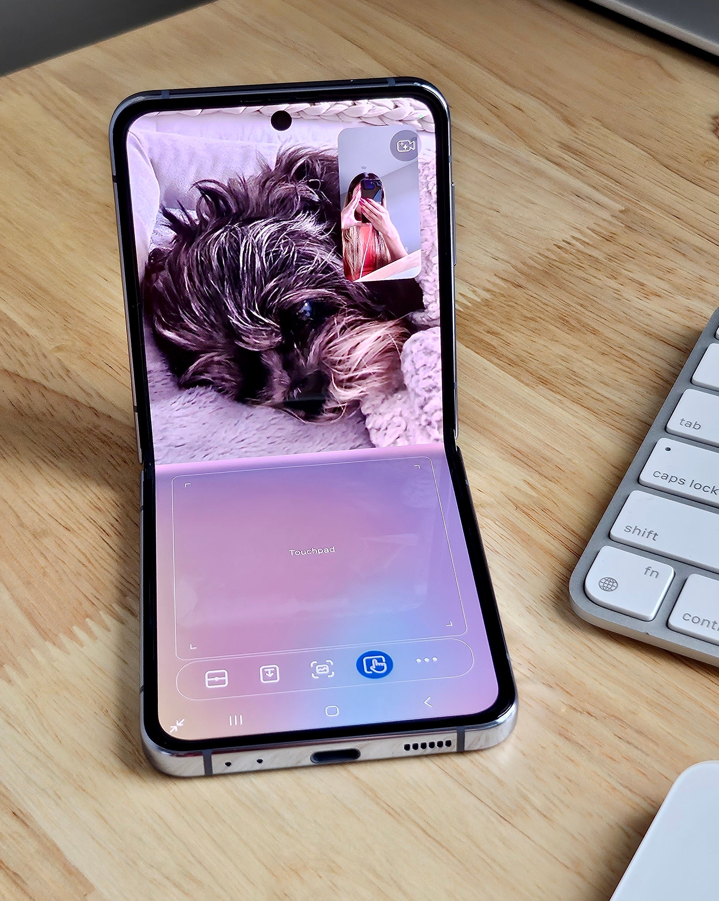 Flip 4 folded at roughly 90 degrees while opened to a video call on the top half and a touchpad with controls on the bottom half of the screen