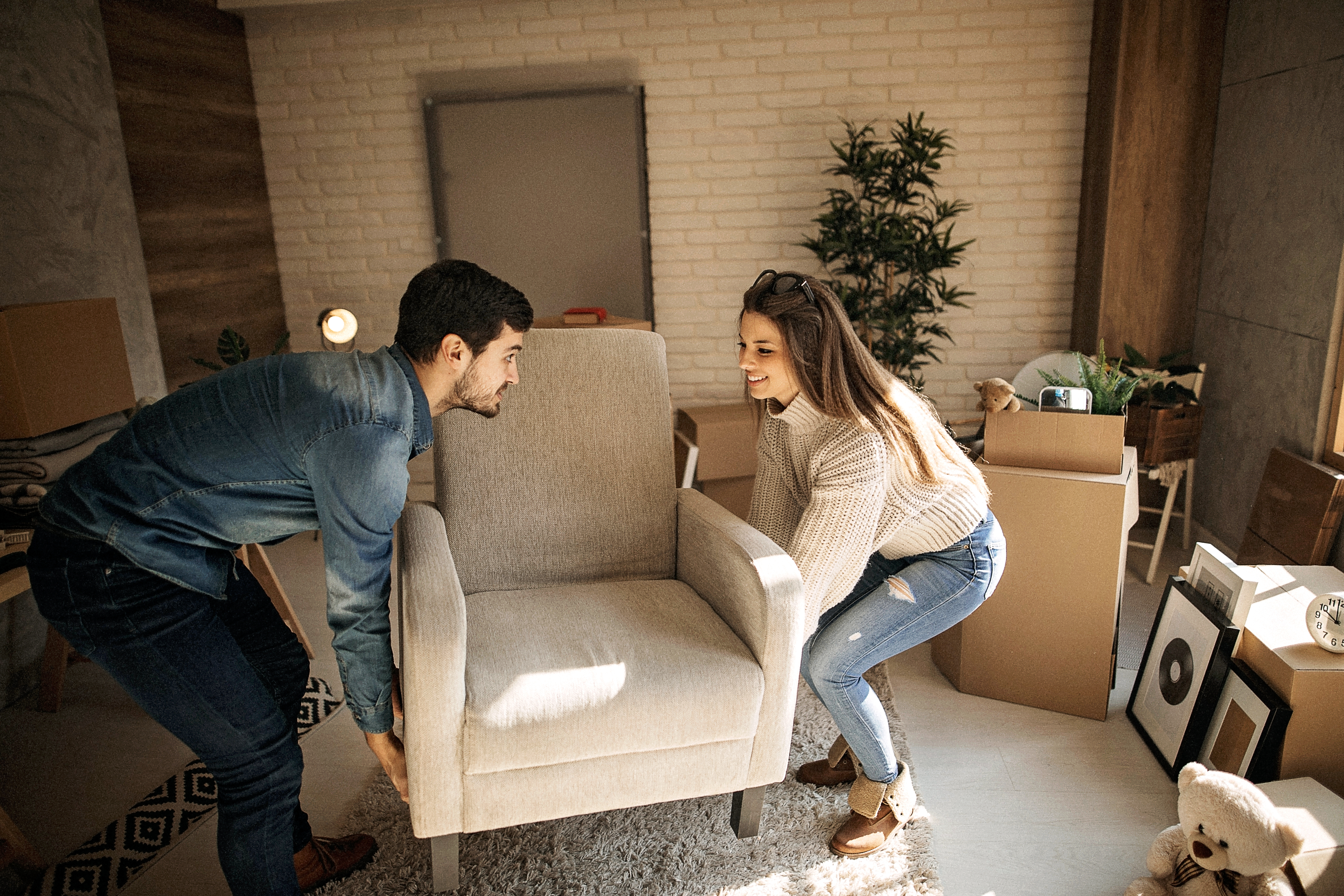Two people moving a new armchair into a room