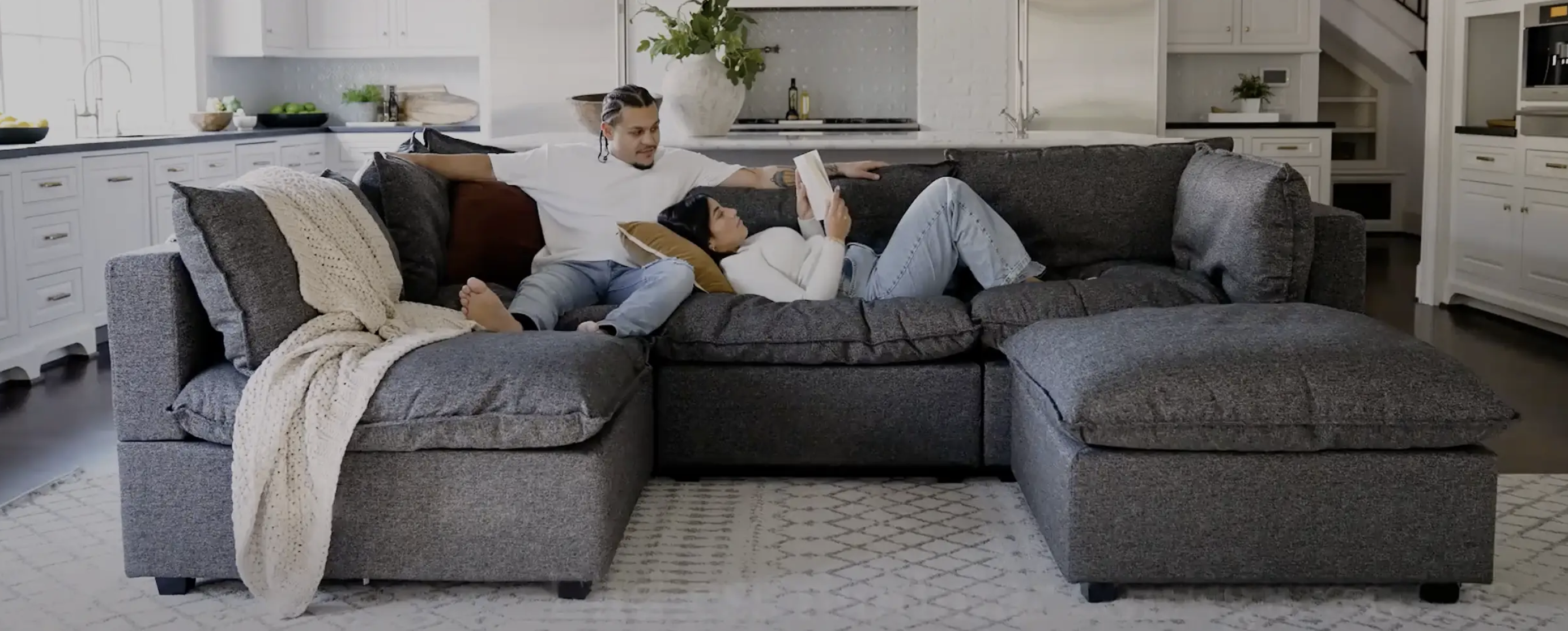 two models on a plush grey sofa