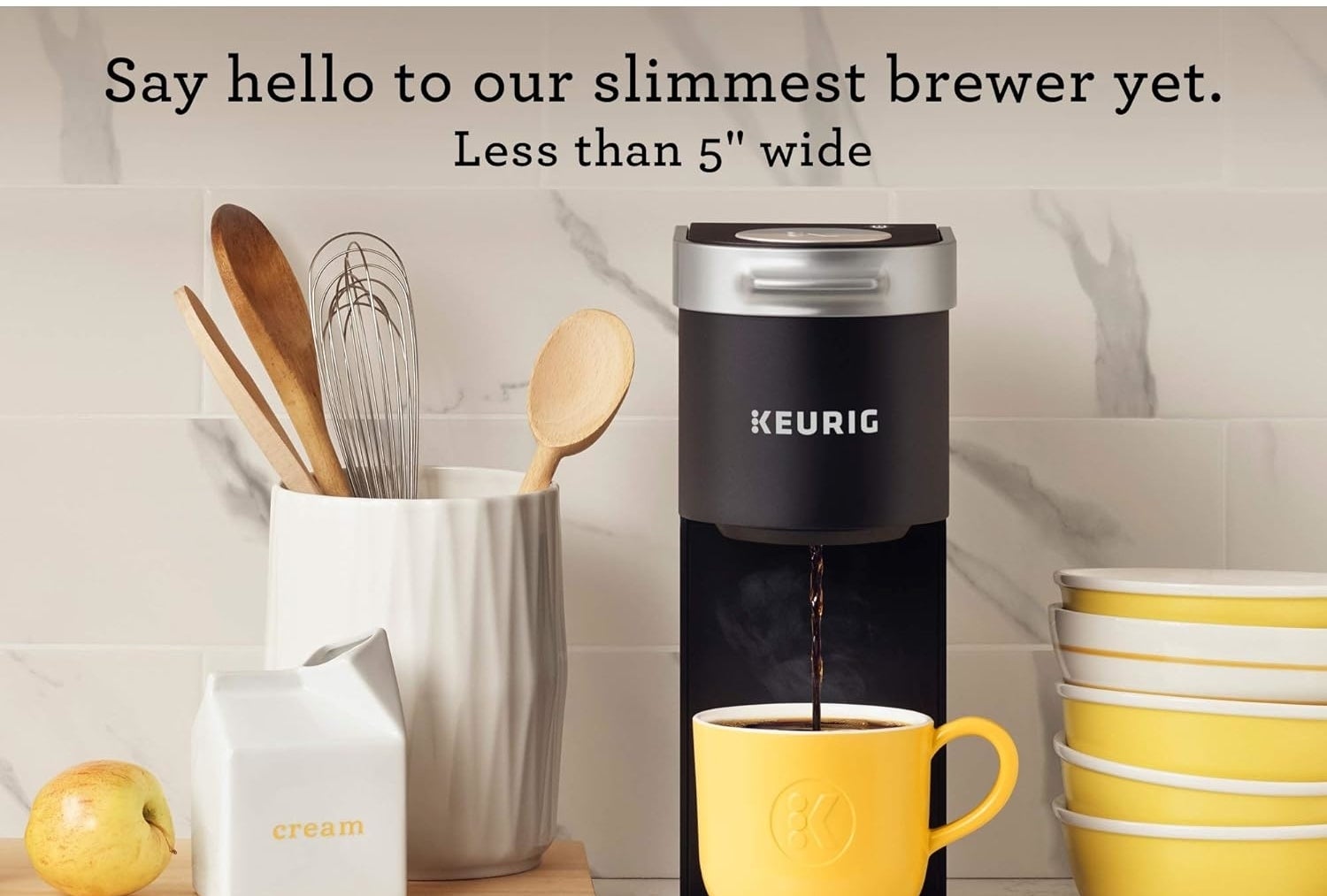 the coffee maker in black sitting on a countertop while coffee dispenses into a cup