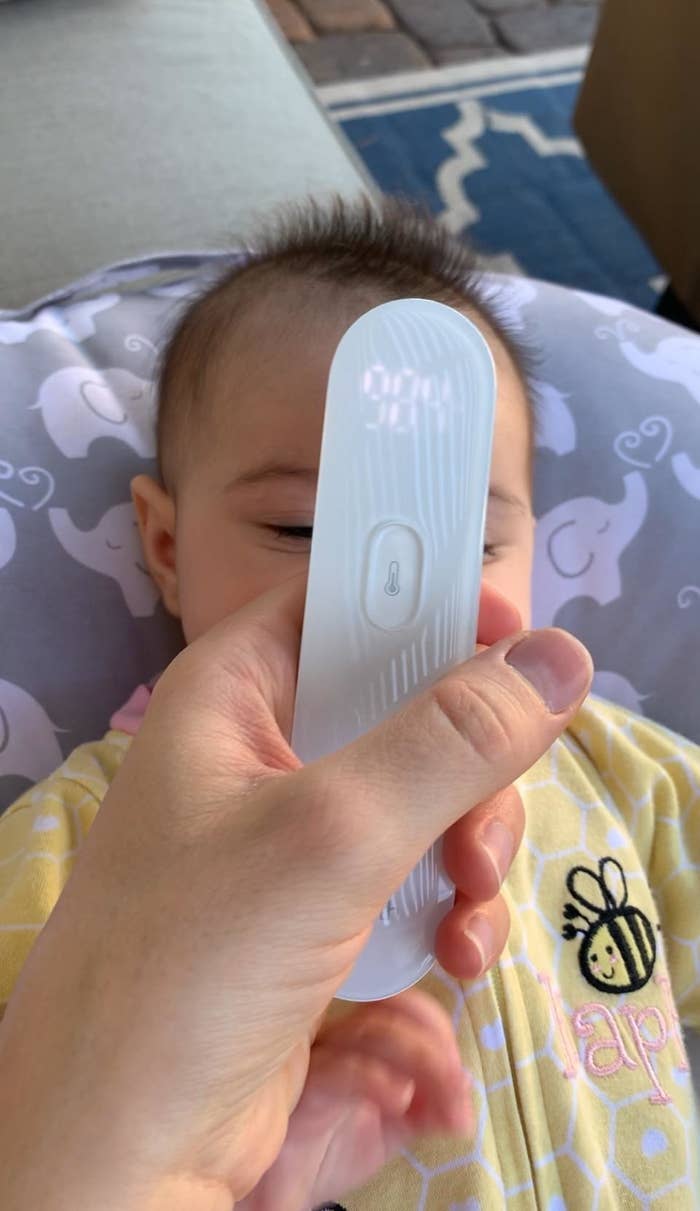 parent reviewer using the white thermometer on their sleeping baby&#x27;s forehead, temp easily reads 98.4