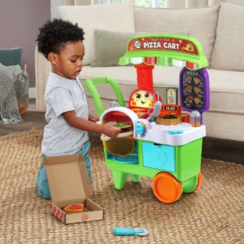 a child playing with a pizza cart toy