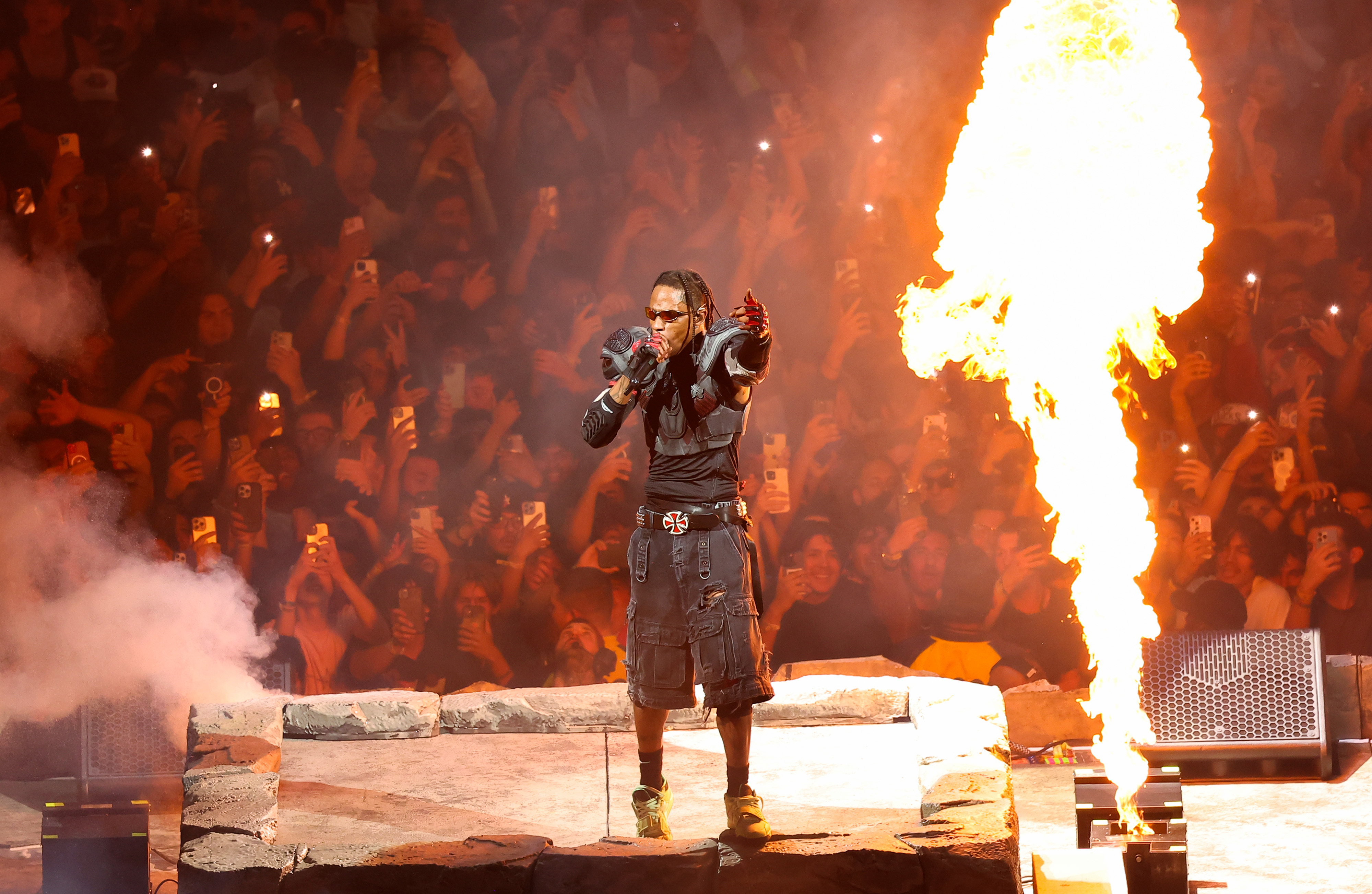 travis performing next to a blaze of fire on stage
