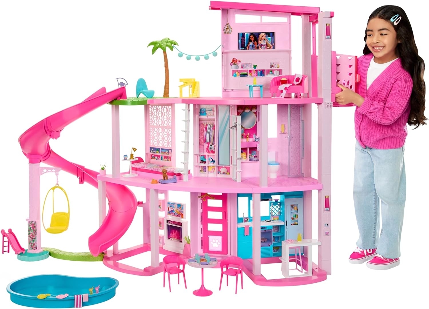 child standing next to three story pink Barbie dollhouse
