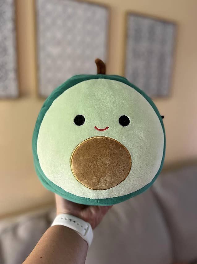 reviewer holding an avocado plushie toy